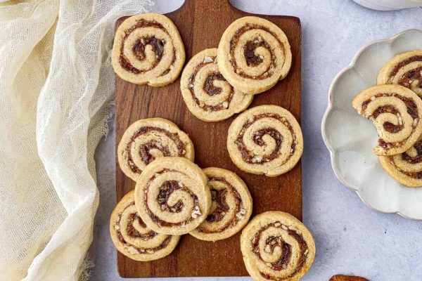 A wooden cutting board with cookies and nuts on it.