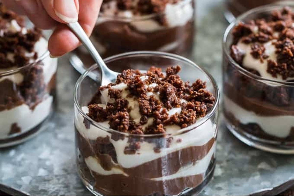 A person holding a spoon in a glass of chocolate pudding, enjoying a festive Christmas treat.