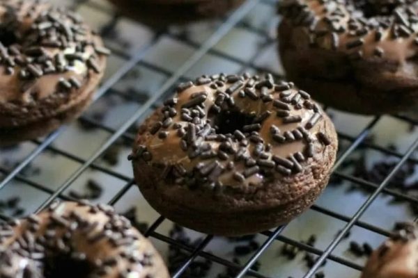 Chocolate donuts with sprinkles on a cooling rack.