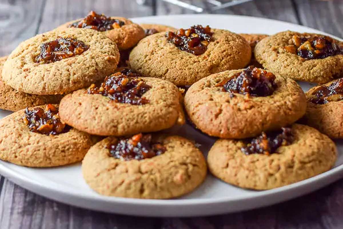 Nut and jam thumbprint mini cookies on a plate.