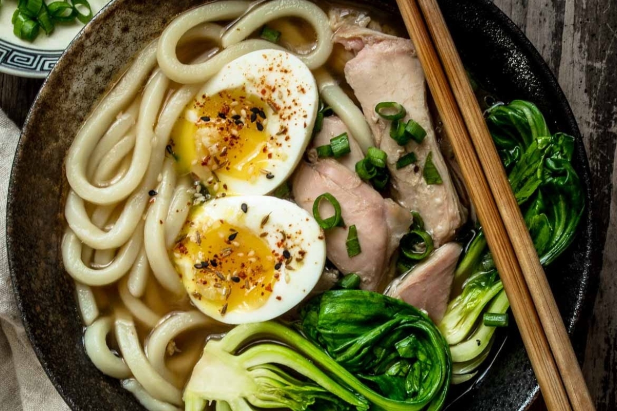 A bowl of asian noodle soup with an egg and greens, perfect for using leftover turkey in a delicious way.