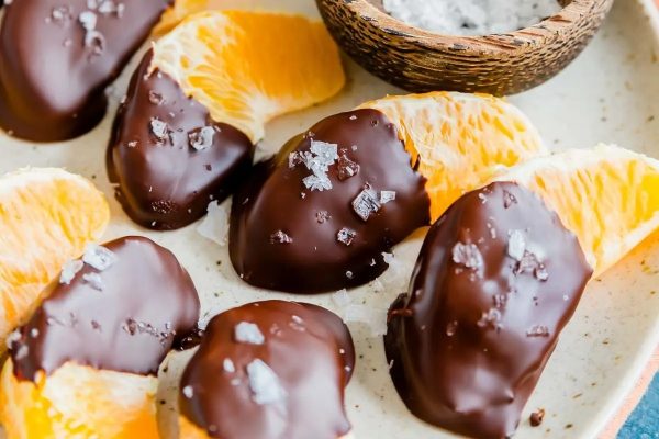 Delicious chocolate covered orange slices arranged on a plate.