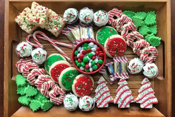 A festive charcuterie board filled with an assortment of Christmas cookies and candies, beautifully presented on a rustic wooden tray.