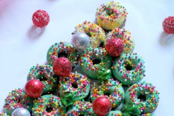 A traditional Christmas tree made of sprinkled donuts.