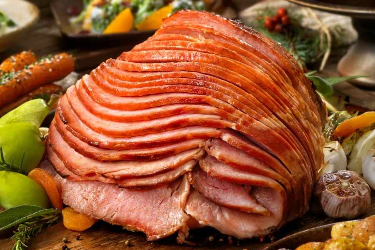 A ham is sitting on a wooden table.