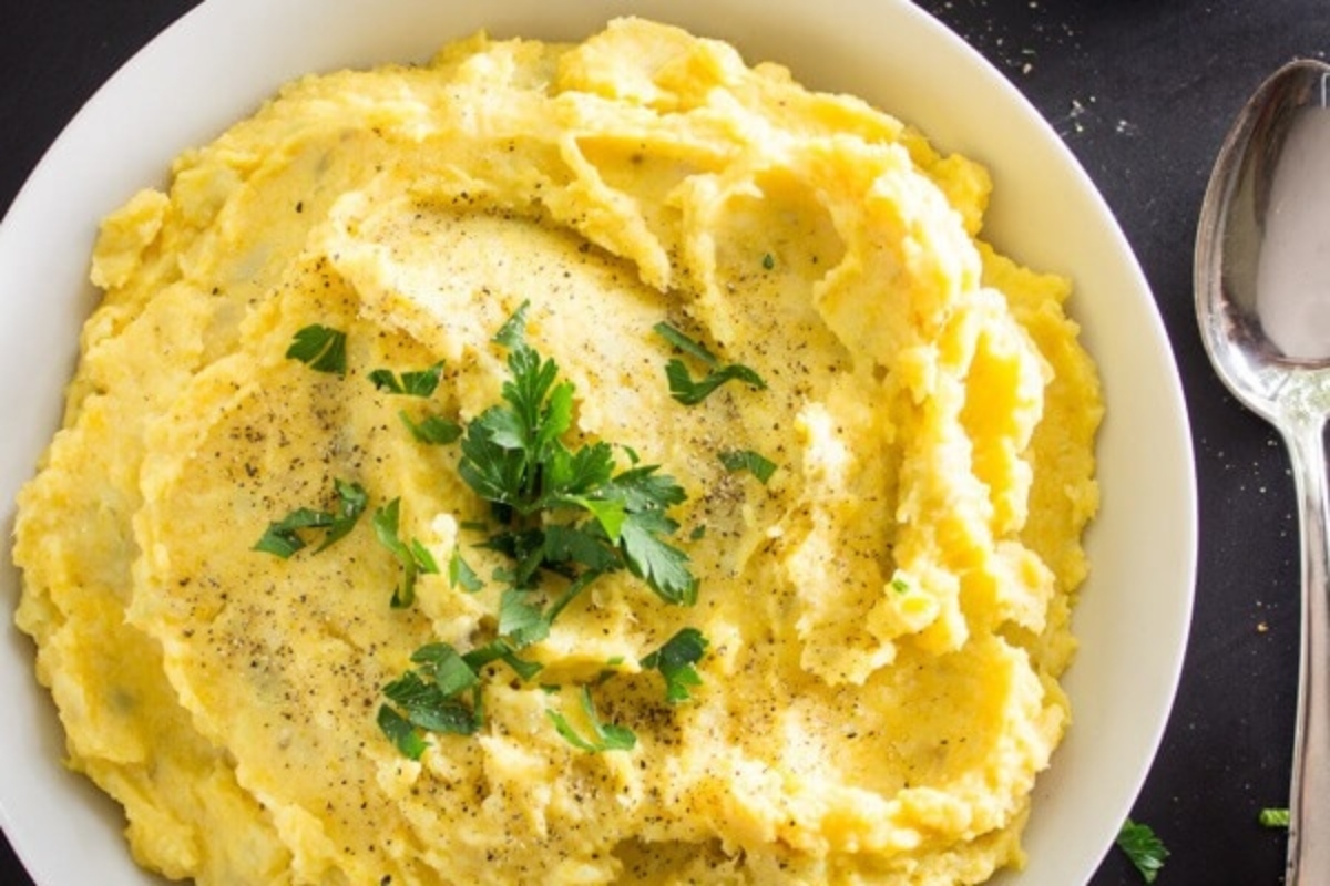A bowl of mashed potatoes topped with fresh parsley.
