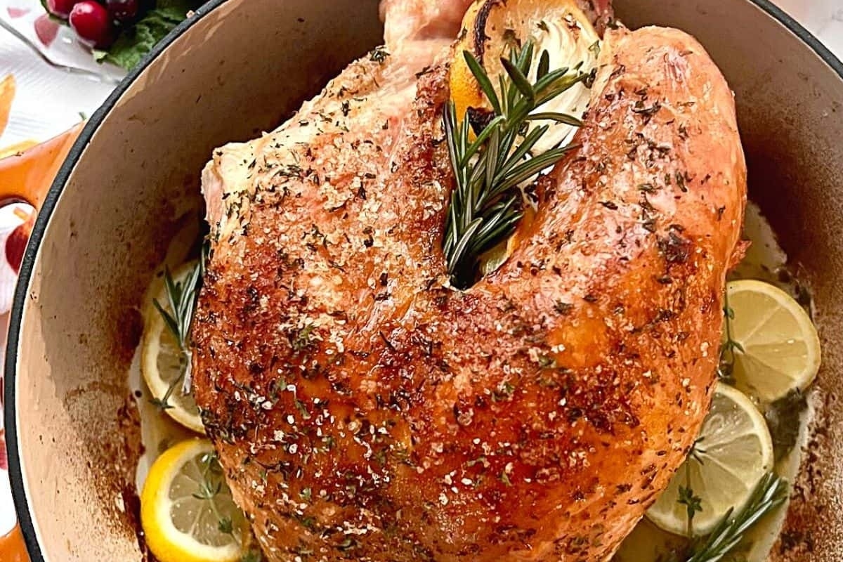 A country-style recipe for Thanksgiving featuring a roast turkey in a pan with lemons and sprigs of rosemary.