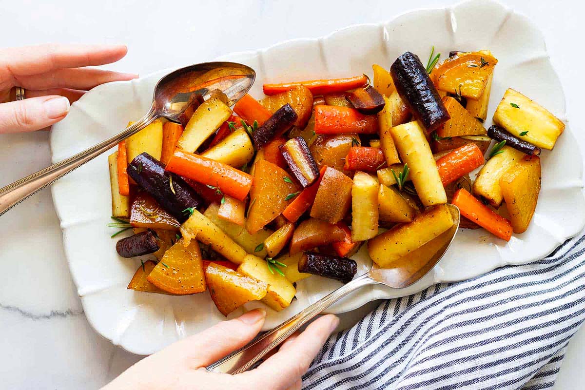 Vegan roasted root vegetables on a white plate, perfect for a vegan Thanksgiving.