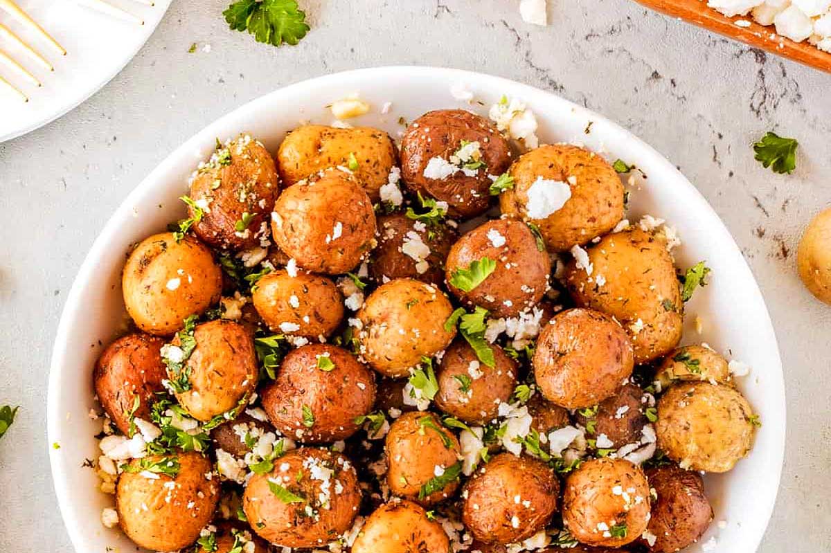 Greek potatoes in a white bowl with parsley and parmesan.