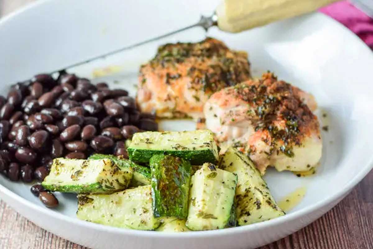 A white bowl with zucchini, chicken, and black beans.