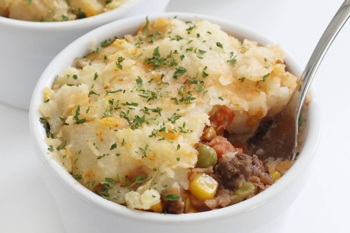 A delectable dish featuring two bowls of mashed potatoes accompanied by a medley of meat and vegetables, including frozen mixed vegetables. Get creative with our flavorful recipes!