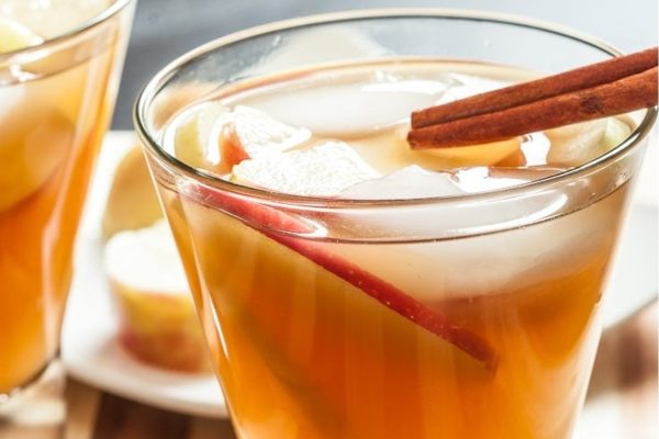Two glasses of apple iced tea with cinnamon sticks.