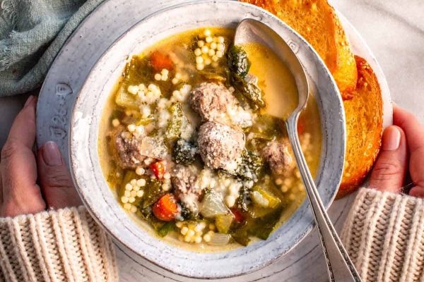 A bowl of soup with meatballs and vegetables.