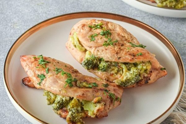Two chicken breasts with broccoli on a plate.
