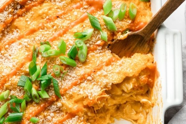 Chicken enchilada casserole recipe in a white dish with a wooden spoon.