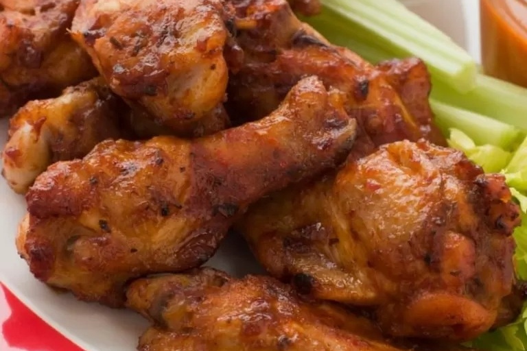Chicken wings on a plate with celery and dipping sauce.