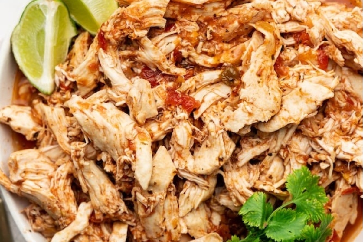Slow Cooker Shredded Chicken in a white bowl with lime and cilantro.
