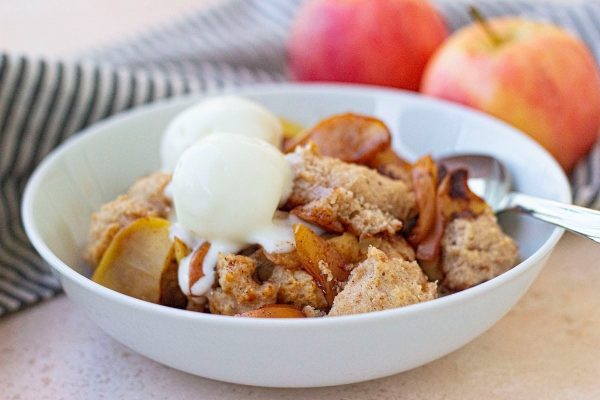 Apple crisp in a bowl with ice cream and apples.