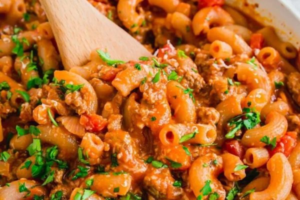 A bowl of pasta with meat and vegetables in it.