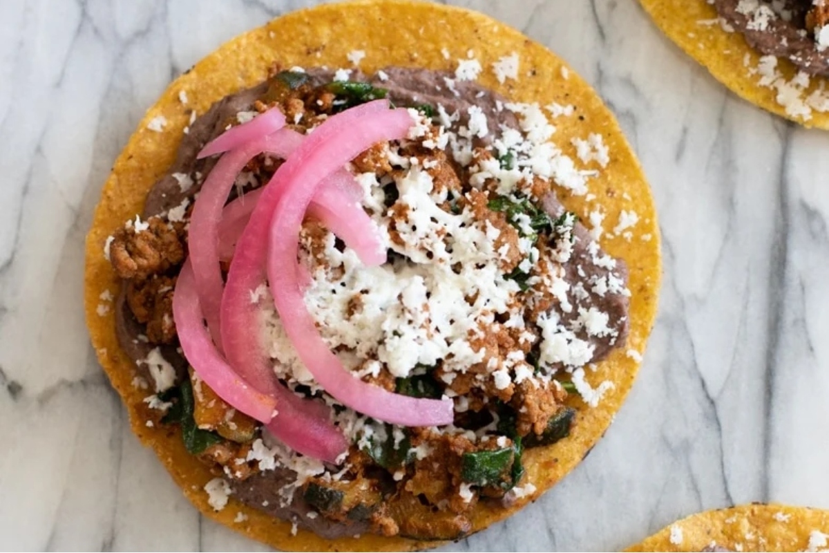 A plate of tacos with ground turkey and onions on top.