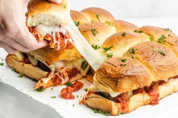 A person is dipping a slice of pizza into a bun.