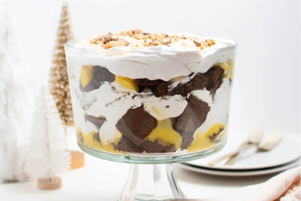 A trifle dessert in a glass bowl with whipped cream and chocolate.