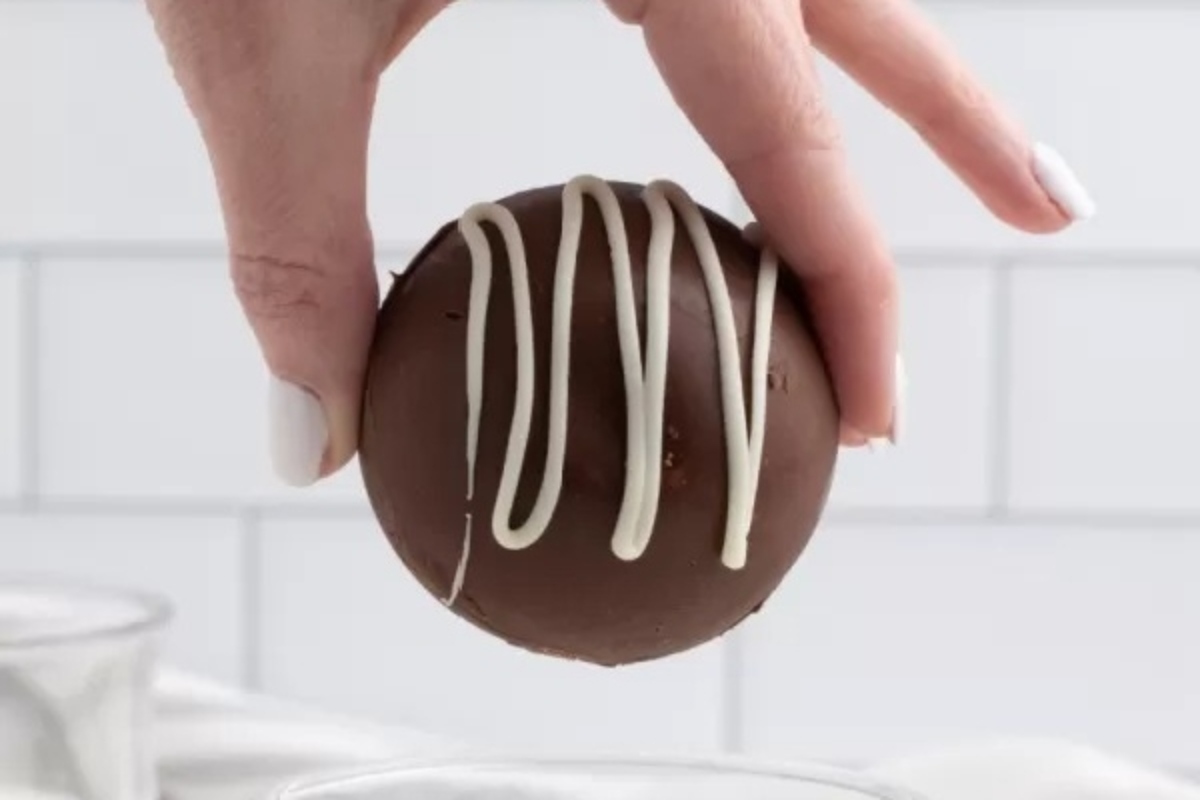 A hand holding a Christmas-themed chocolate egg with white icing, creating an edible gift.