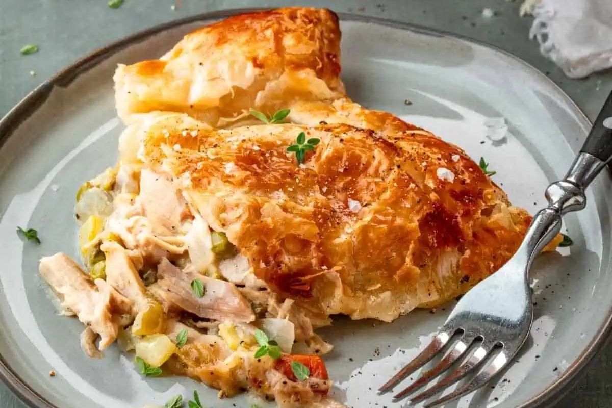 Puff pastry chicken pot pie on a plate with a fork.