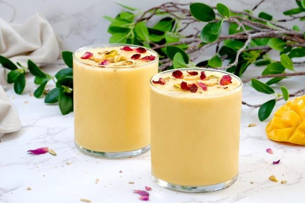 Two glasses of mango smoothie on a marble table, perfect for refreshing milkshake recipes.