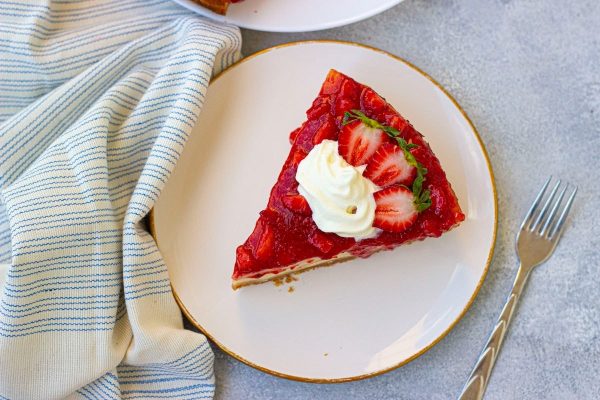 A slice of strawberry cheesecake on a plate.