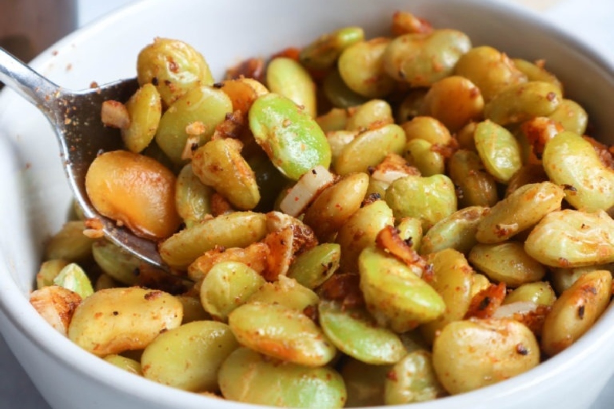 Country style green beans in a white bowl with a spoon.