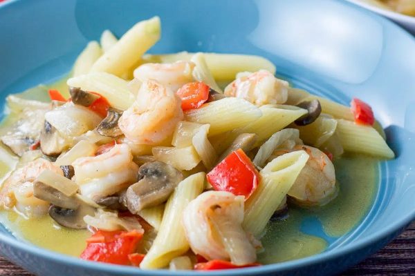 A bowl of pasta with shrimp, mushrooms and peppers.