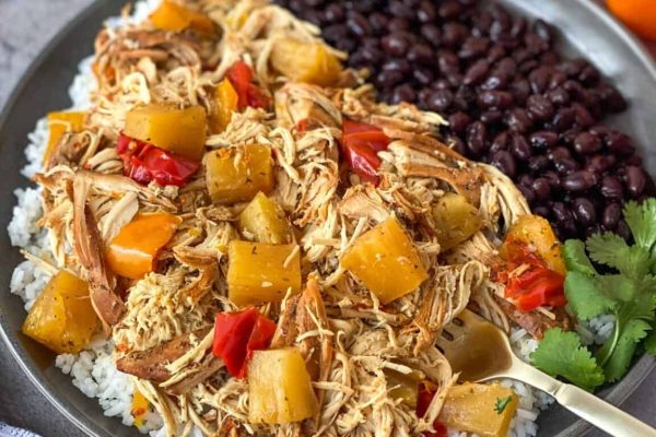 A plate of chicken and rice with pineapples and black beans.