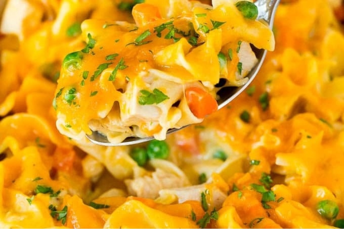 A spoonful of leftover turkey noodle casserole in a casserole dish.