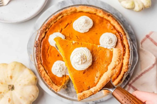 A slice of pumpkin pie with whipped cream on top.