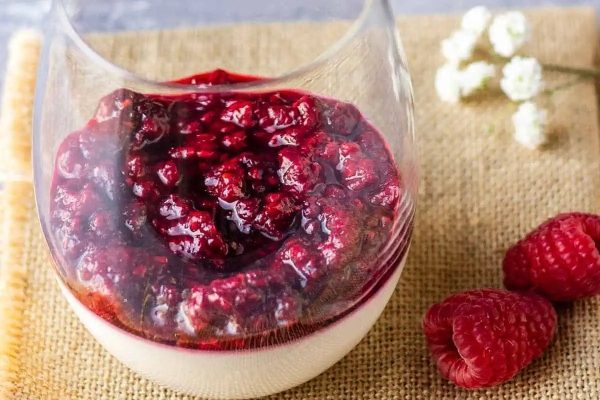 A glass filled with raspberry yogurt and raspberries, a delightful dessert option layered with fruity goodness.
