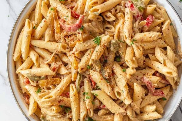 Penne pasta with chicken and peppers in a white dish. This delicious recipe combines penne pasta with chicken and peppers to create a flavorful and satisfying meal.