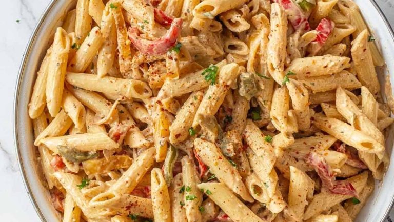 Penne pasta with chicken and peppers in a white dish. This delicious recipe combines penne pasta with chicken and peppers to create a flavorful and satisfying meal.