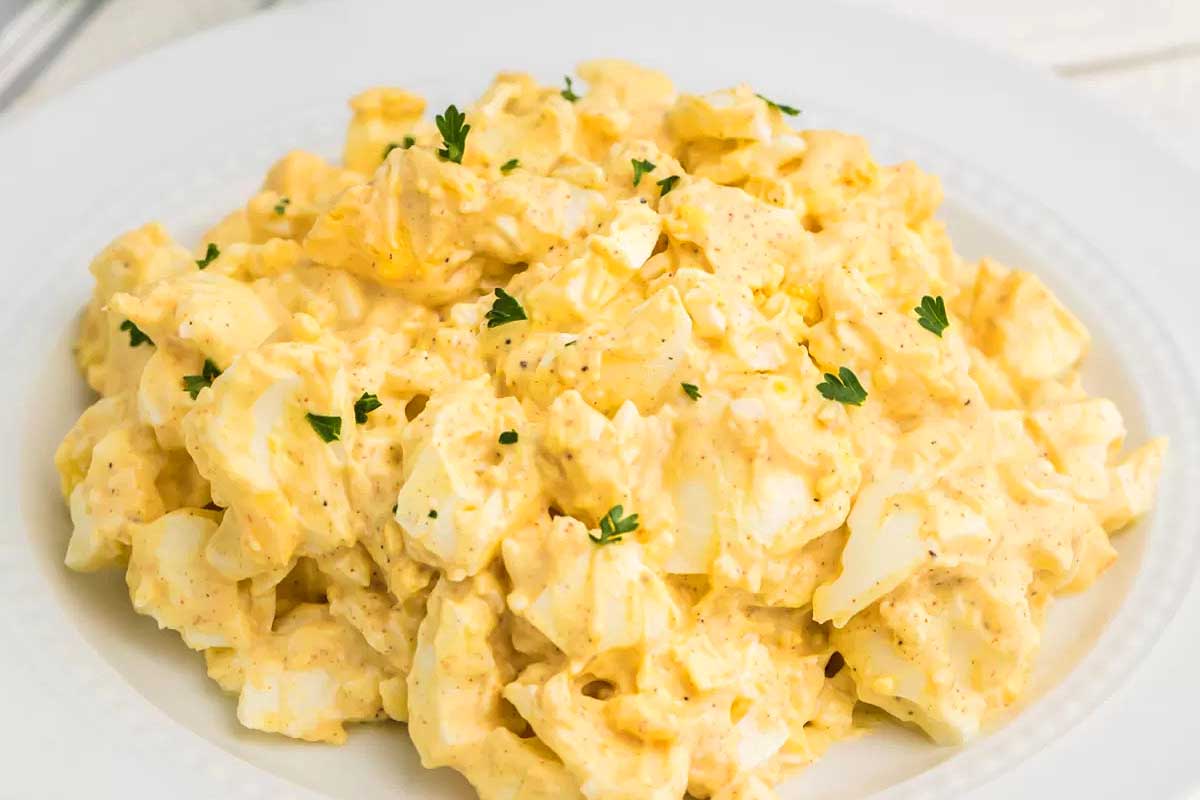 Egg salad on a white plate with a fork.
