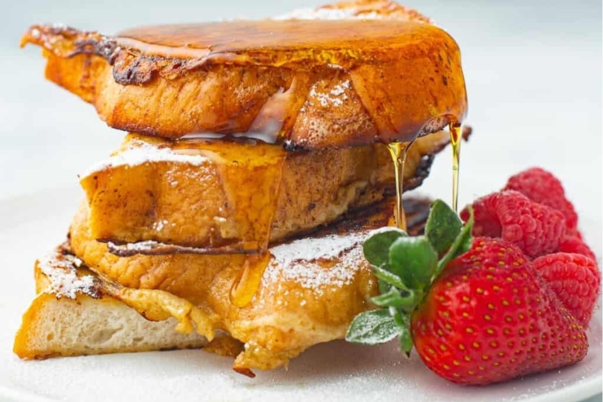 A delicious breakfast recipe for Christmas: a stack of french toast served with syrup and strawberries.