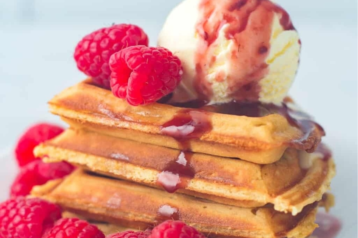 A stack of waffles with ice cream and raspberries, perfect for a festive Christmas breakfast.