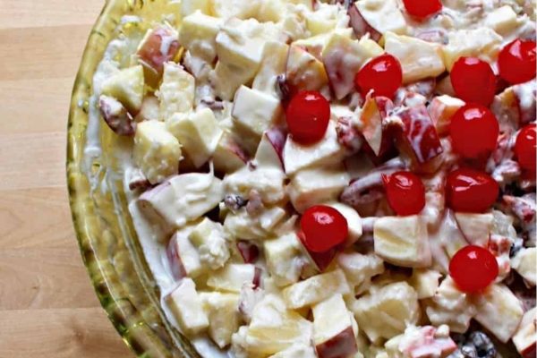 A colorful bowl of fruit salad with cherries on top.