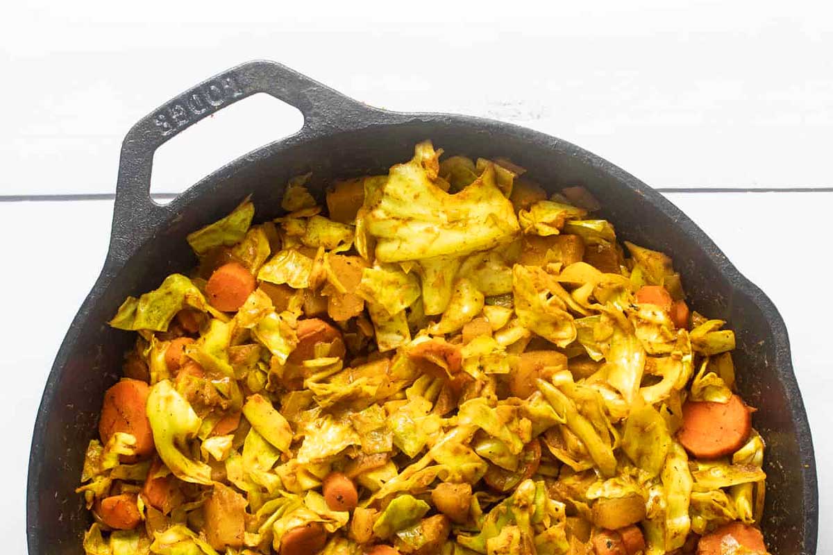 A cast iron skillet filled with cabbage and carrots.
