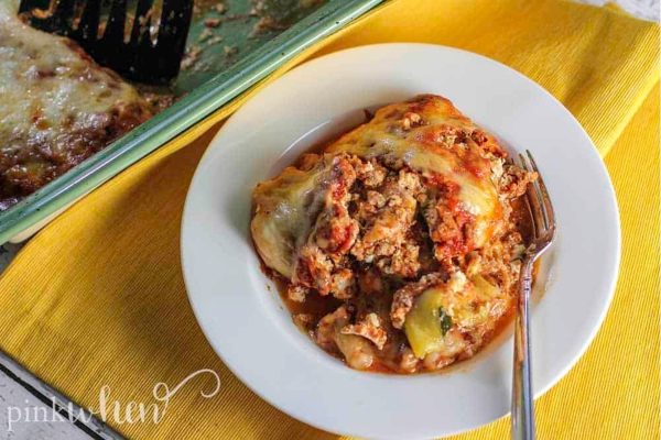 A plate of lasagna with meat on it.