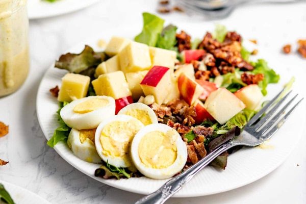 A plate with a salad and an egg on it.
