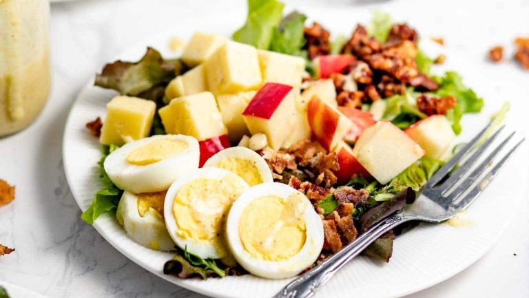 A plate with a salad and an egg on it.