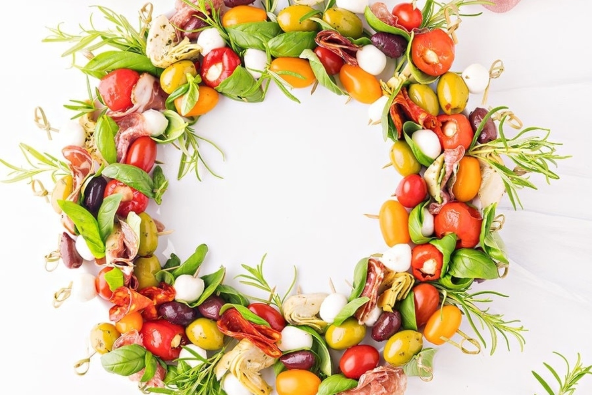 A Christmas wreath of vegetables and herbs on a white background.