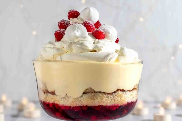 A delectable trifle dessert decorated with luscious whipped cream and fresh raspberries.