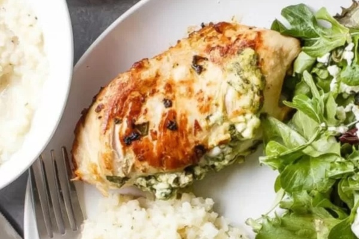 A plate with a chicken breast, salad and rice.
