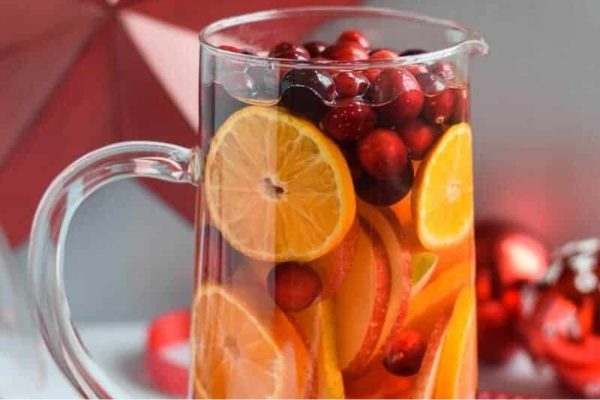 A pitcher of cranberry sangria with oranges and cranberries.